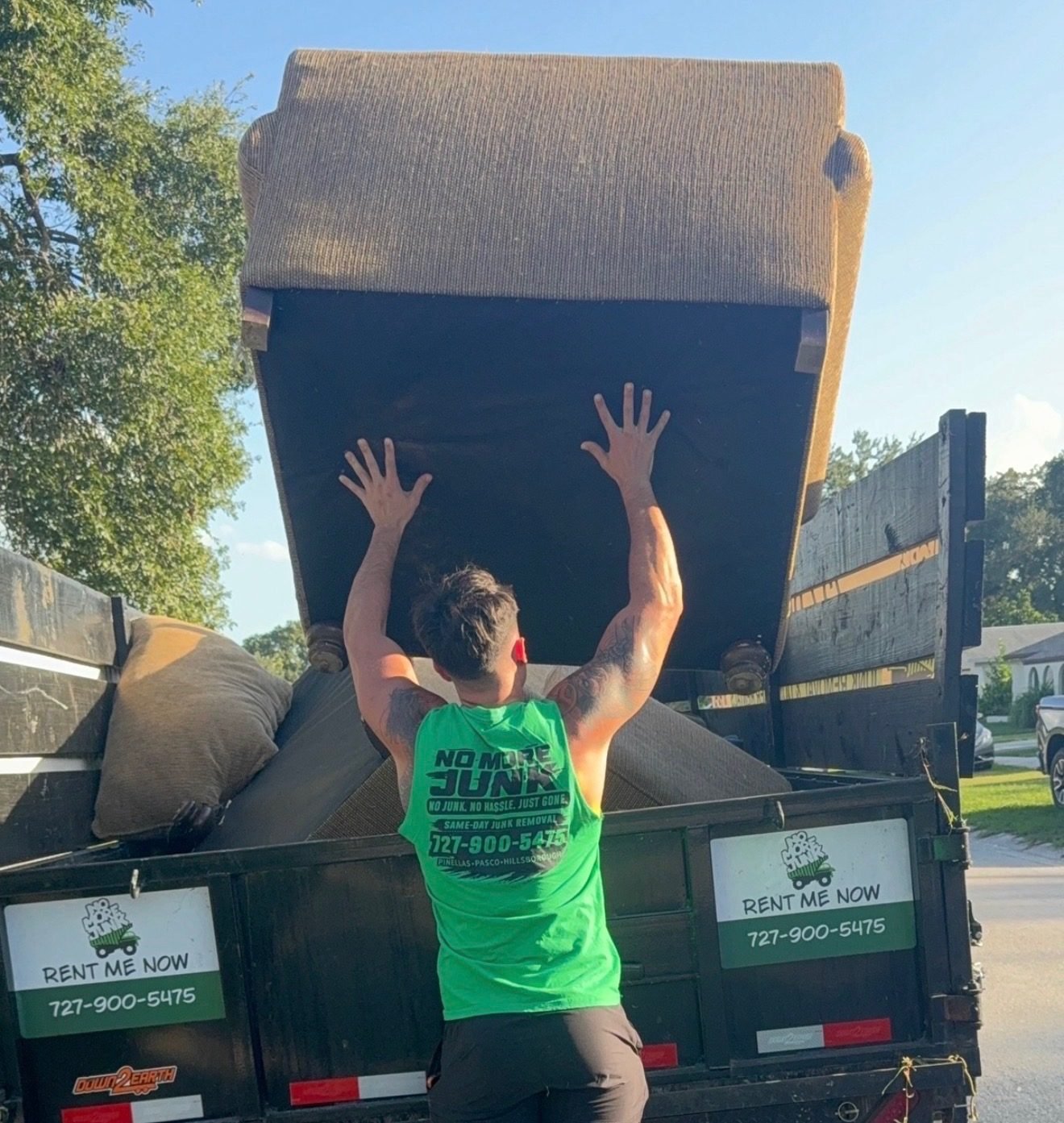 No More Junk crew loading a bulky sofa into a branded dump trailer during junk removal in Largo, FL 33771