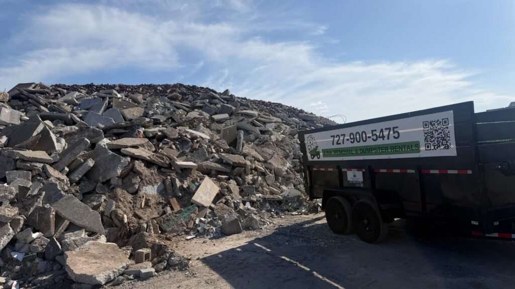 Branded dump trailer beside a large construction debris pile before hauling in Tarpon Springs, FL 34689