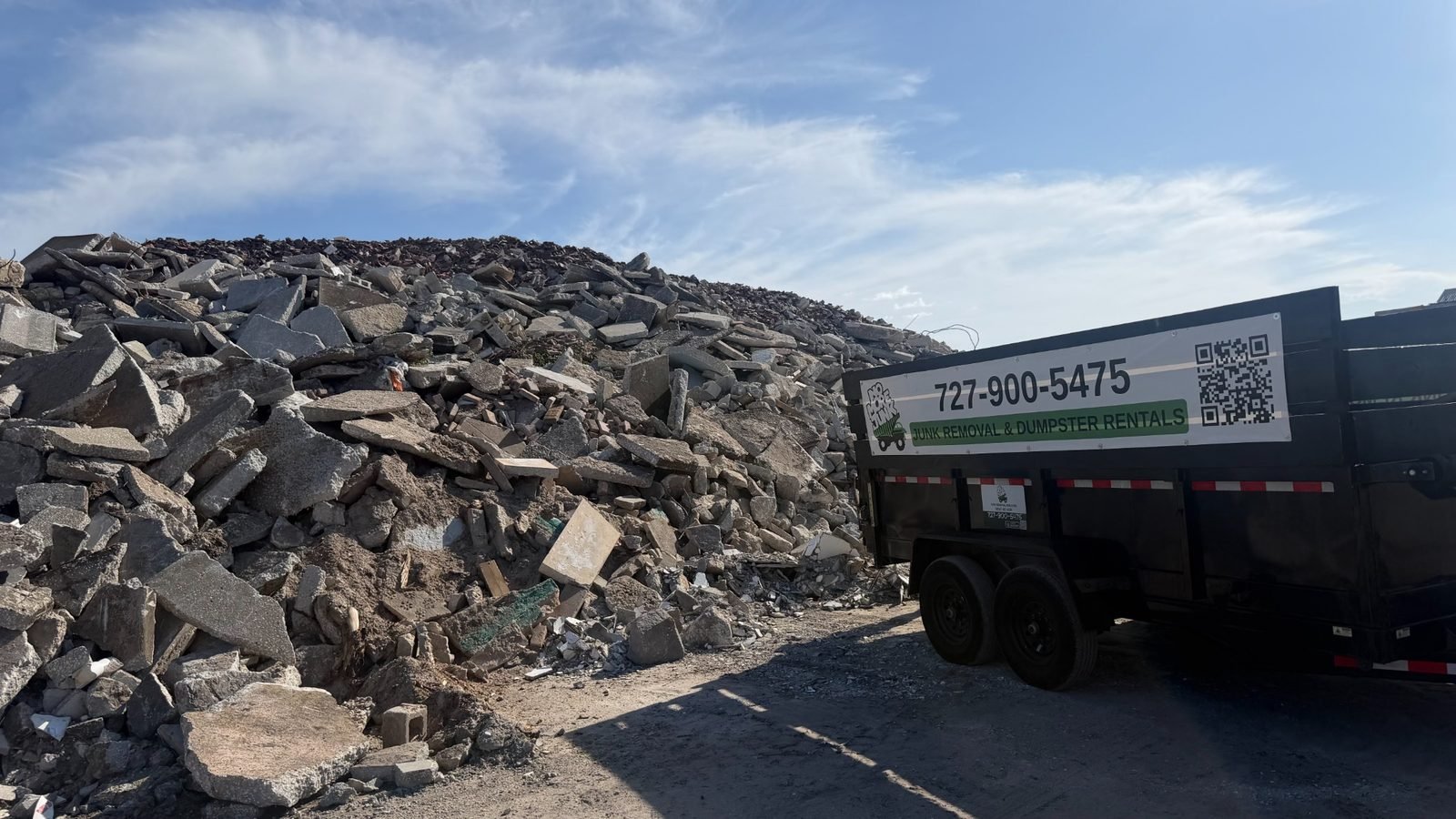 Branded dump trailer beside a large construction debris pile before hauling in Tarpon Springs, FL 34689