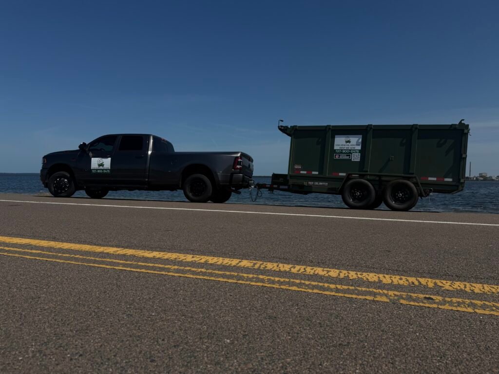 Green and black No More Junk truck and dump trailer parked in Tarpon Springs.