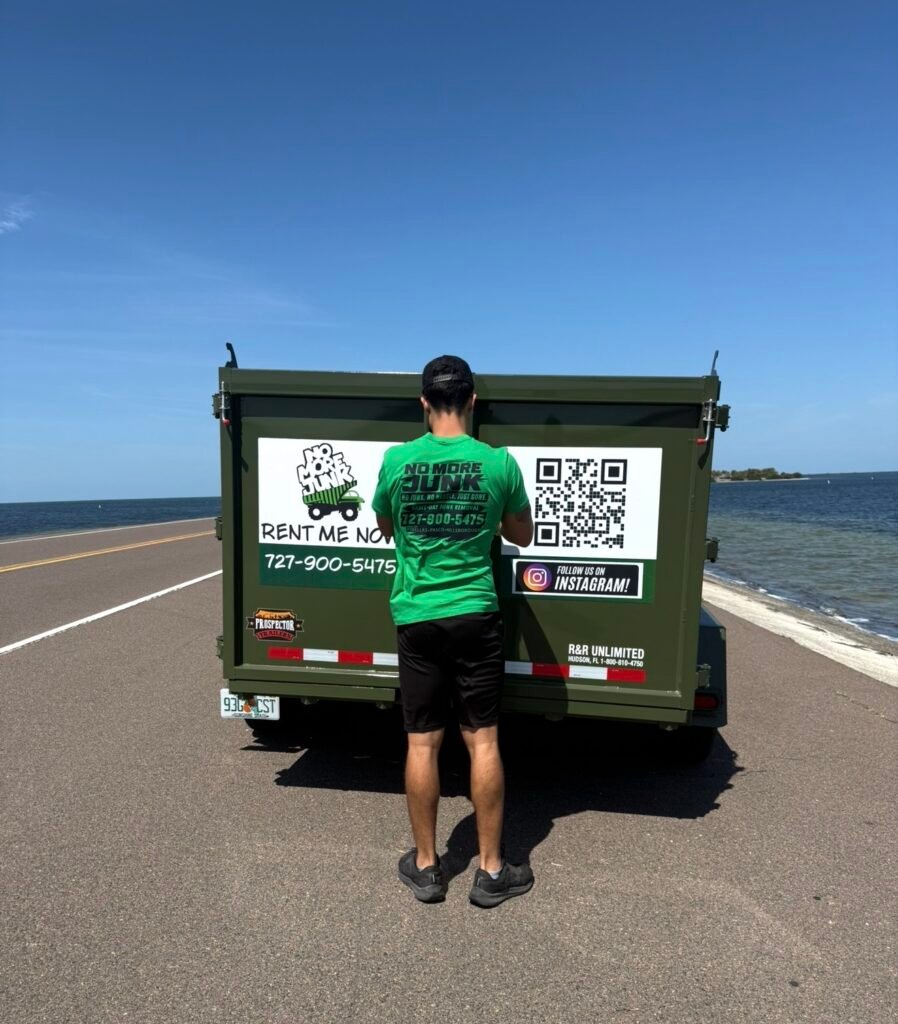 Owner of No More Junk standing with branded dump trailer in Tarpon Springs FL
