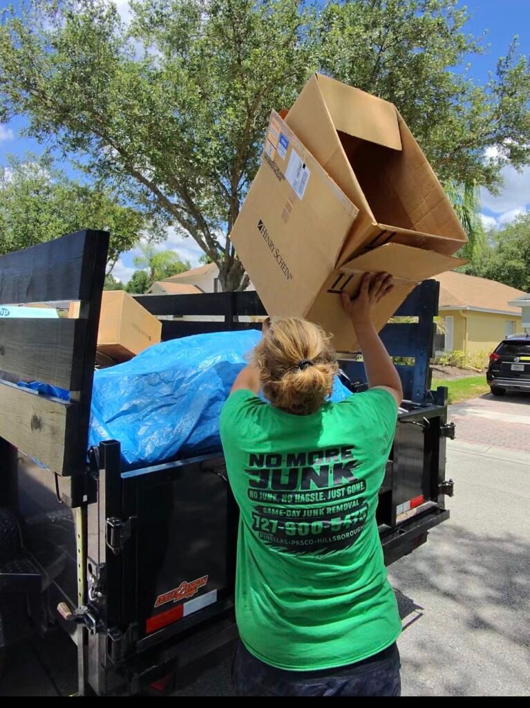 No More Junk team loading household junk and debris into a dump trailer during a junk removal job in Palm Harbor, Florida.