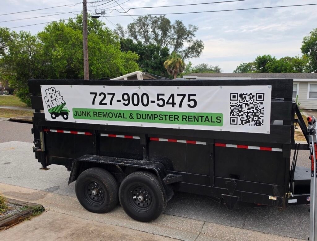 No More Junk branded dump trailer parked in Tarpon Springs, FL, providing junk removal, property cleanouts, and dump trailer rental services.
