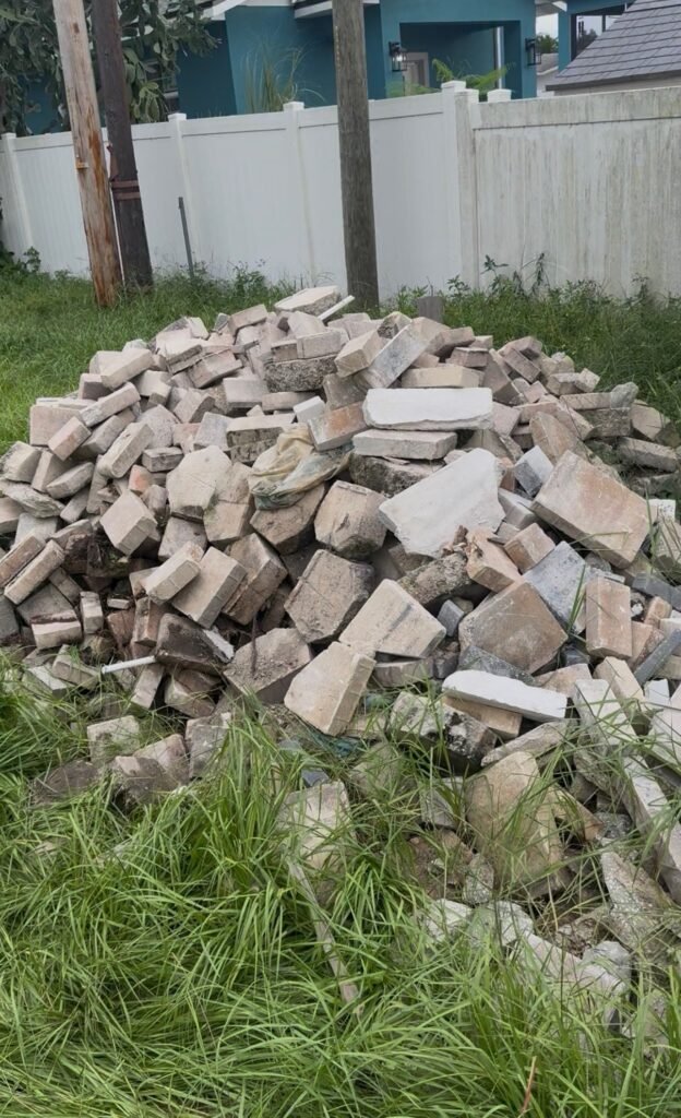 Pile of broken pavers and masonry in a Trinity yard before debris removal