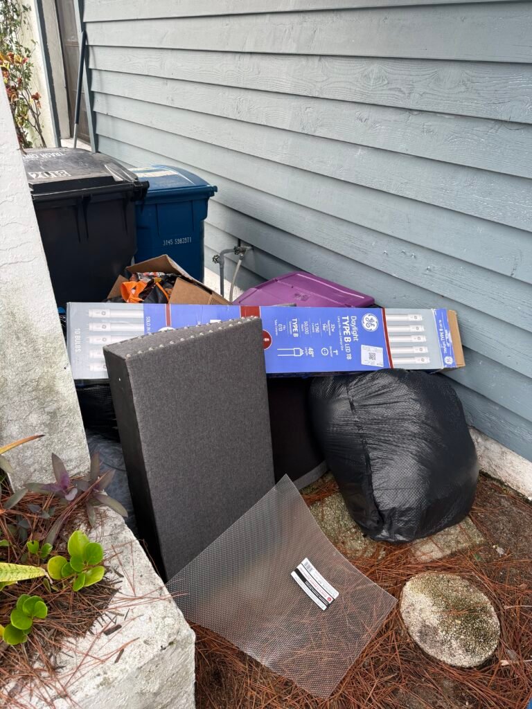 Bagged junk, boxes and discarded items beside bins before a Trinity residential cleanup