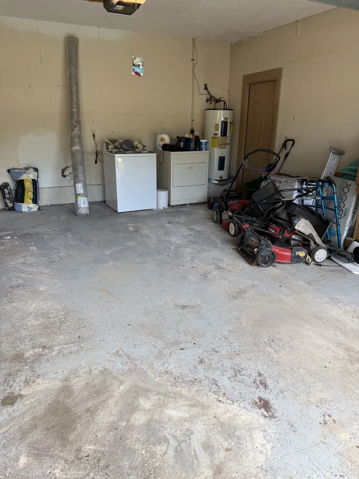 Cleared garage floor with laundry appliances and lawn equipment remaining along the walls.
