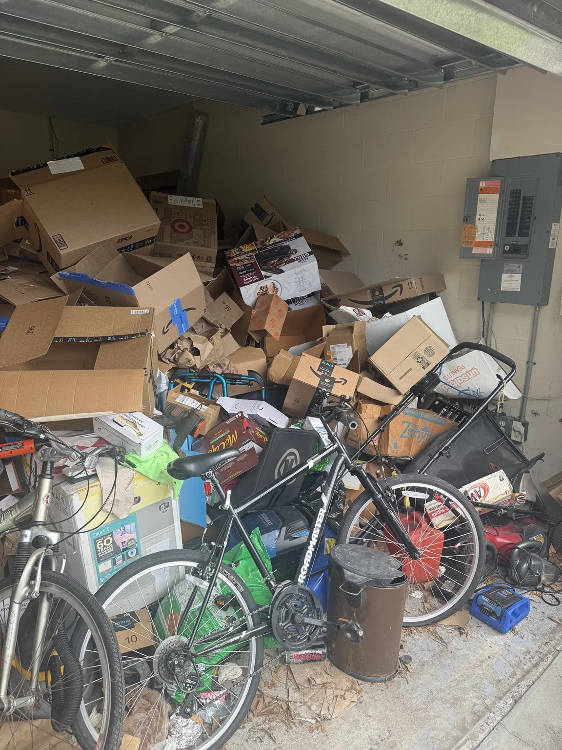 Cardboard boxes, bicycles and stored household items filling a garage before cleanout.