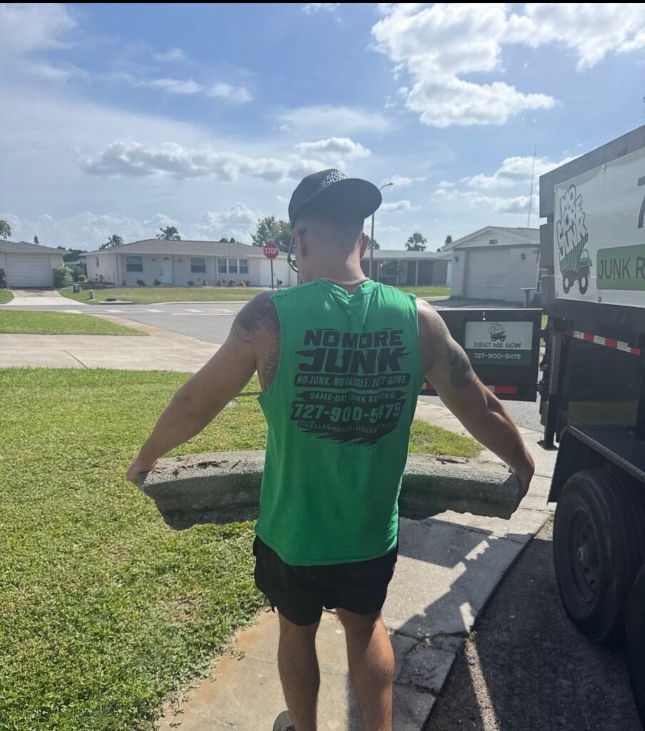 No More Junk crew member carrying debris beside the branded trailer in a Florida residential neighborhood
